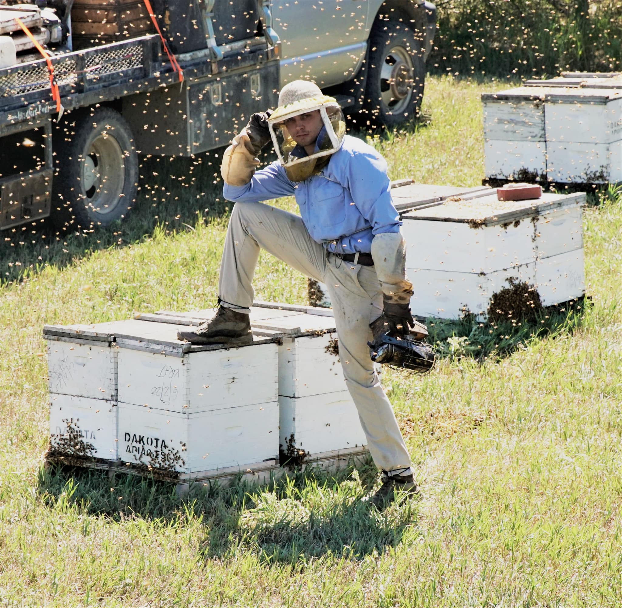 Zach Pederson posing next to bee hives.